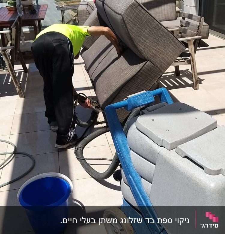 אדם מנקה ספה עם מכונת ניקוי מקצועית